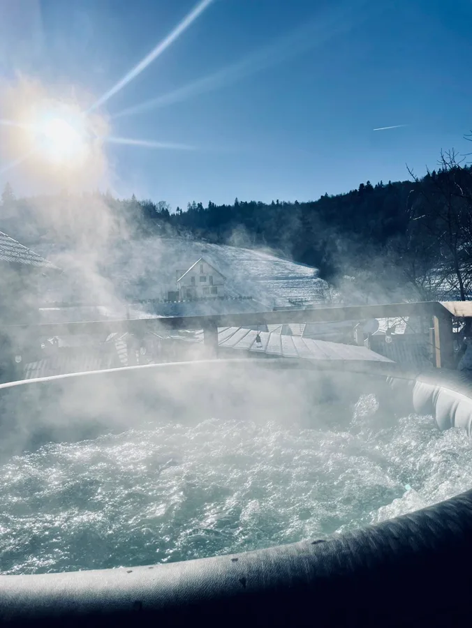 Jacuzzi cu aburi iarna — priveliște la sat sub zăpadă